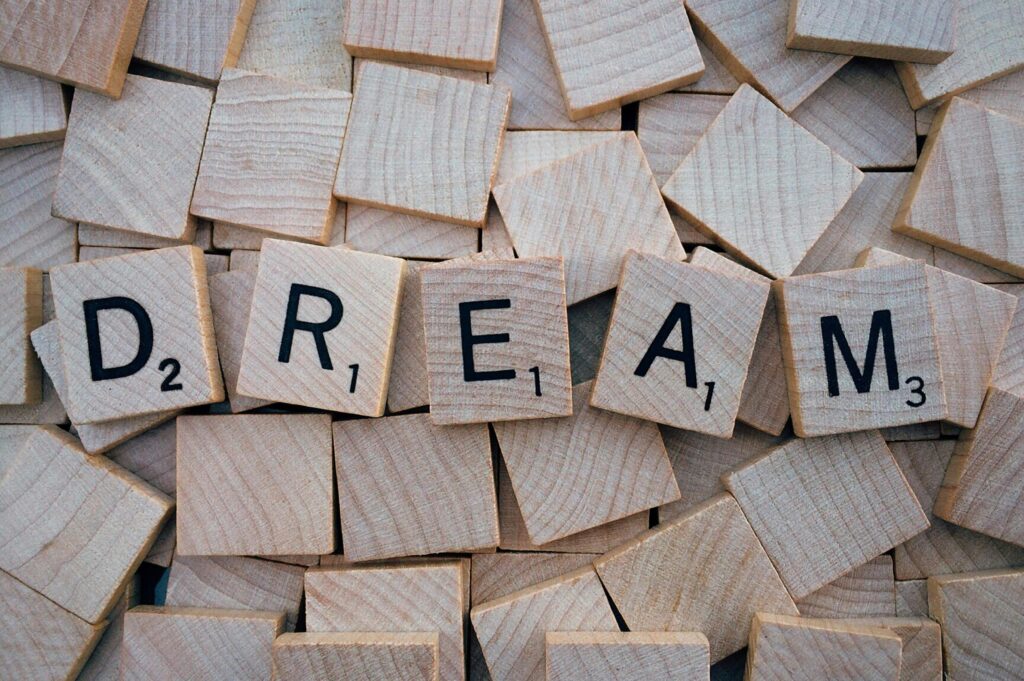 Close-up of wooden Scrabble tiles spelling the word 'DREAM', symbolizing creativity and imagination.
